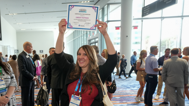 Happy woman holding certificate over her head.