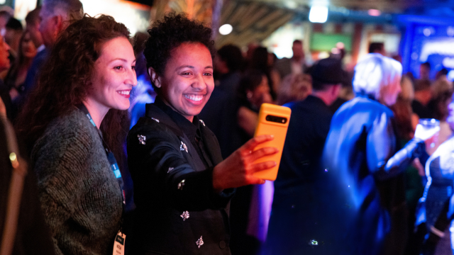 Two women taking a picture an event.