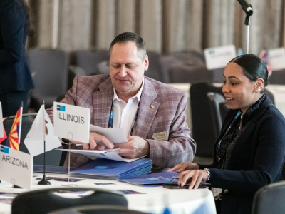 Man and woman at a table with signs and folders.